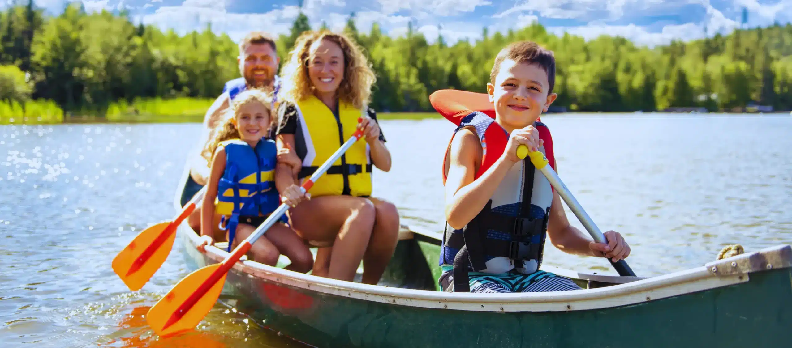 famille heureuse faisant du canoe sur lac sourires scaled